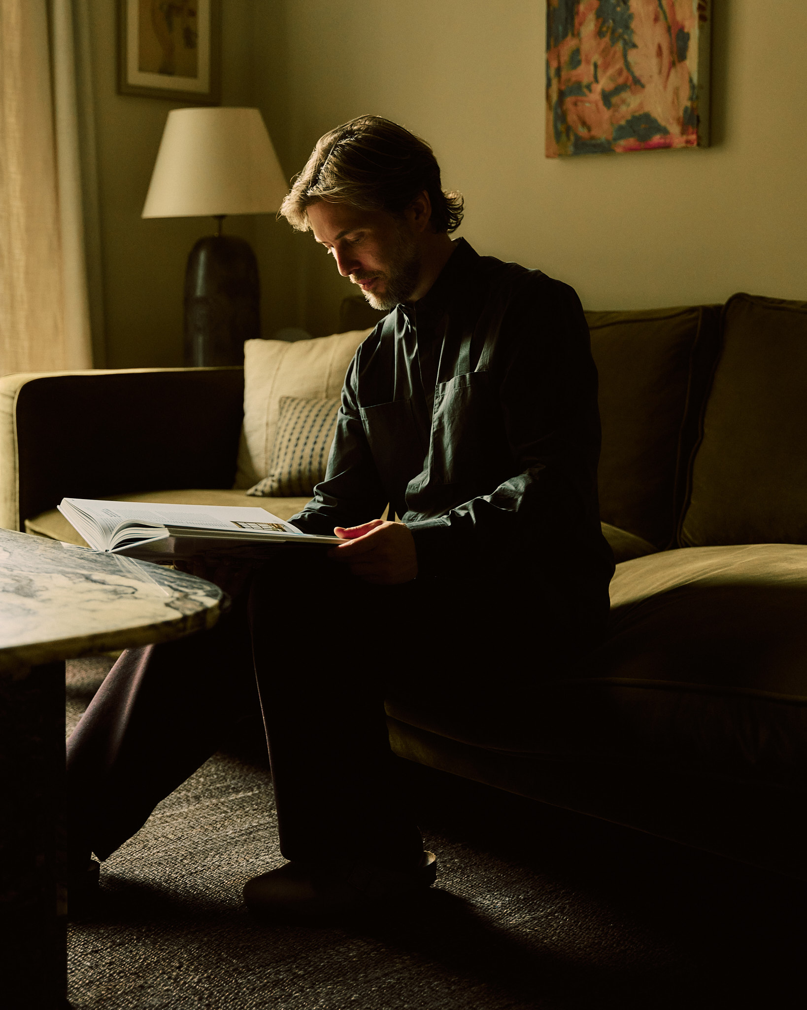 Johan Seferlis seated with a design book in the Wintergreen interior